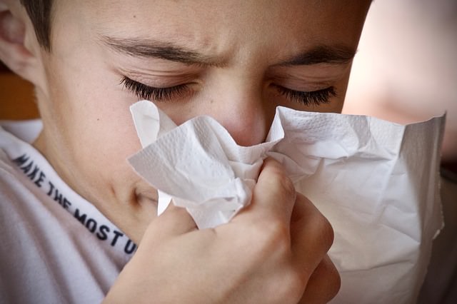 Child sneezing into tissue